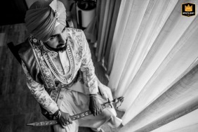 Isla Mujeres, Mexico, provides the intimate setting for the last moments of calm as a groom quietly sits alone near a curtain-covered window, reflecting before his wedding day officially begins.